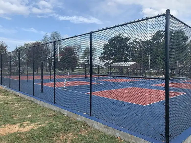 Black vinyl coated chain link enclosure around pickleball courts in Tontitown