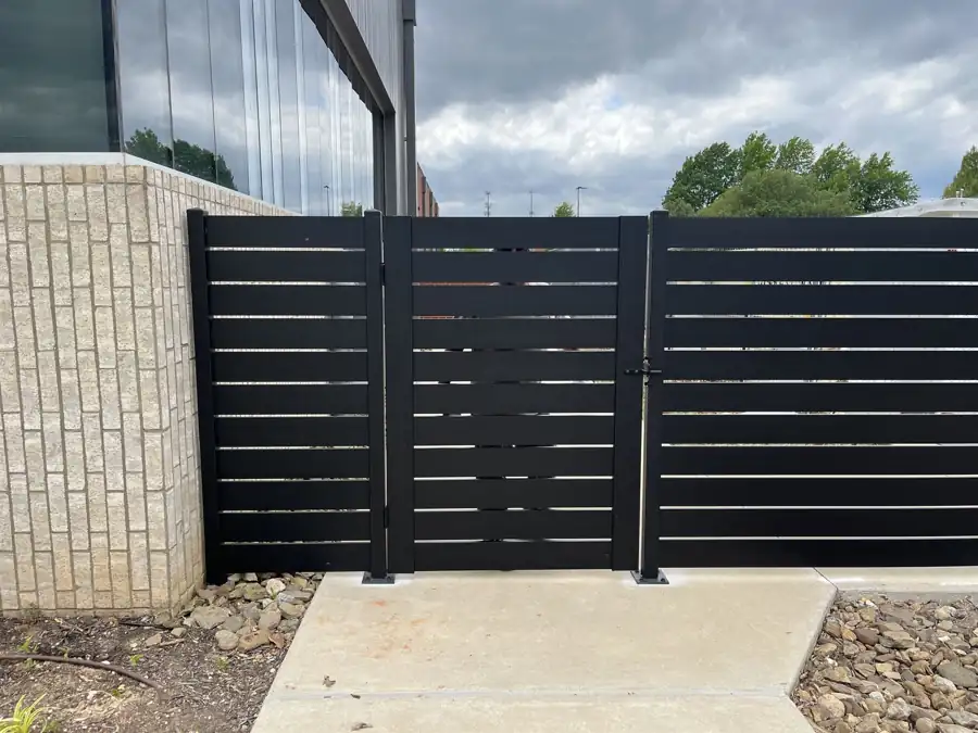 Black horizontal slat aluminum screen fence and gate at a Bentonville commercial building
