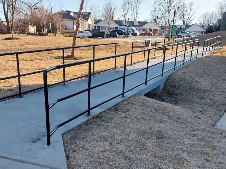 Black two rail steel handrail along a curving trail ramp in Bentonville