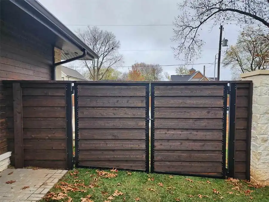 Dark stained horizontal wood privacy fence with a black framed gate beside a Bentonville home