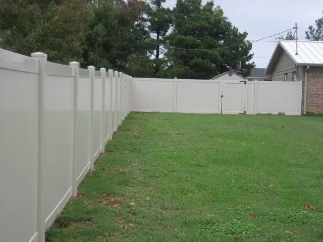 Tan vinyl privacy fence around a Fayetteville back yard ending at a walk gate