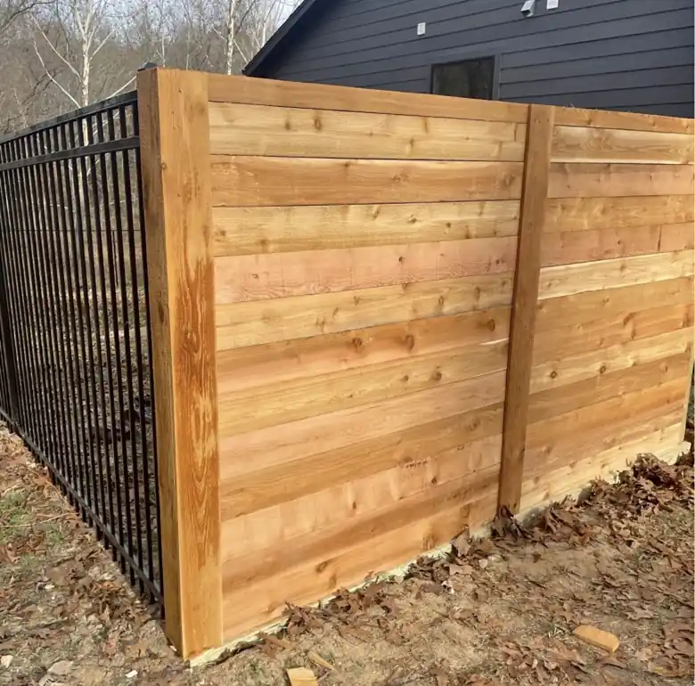 Horizontal cedar privacy panel meeting a black ornamental fence in Bella Vista
